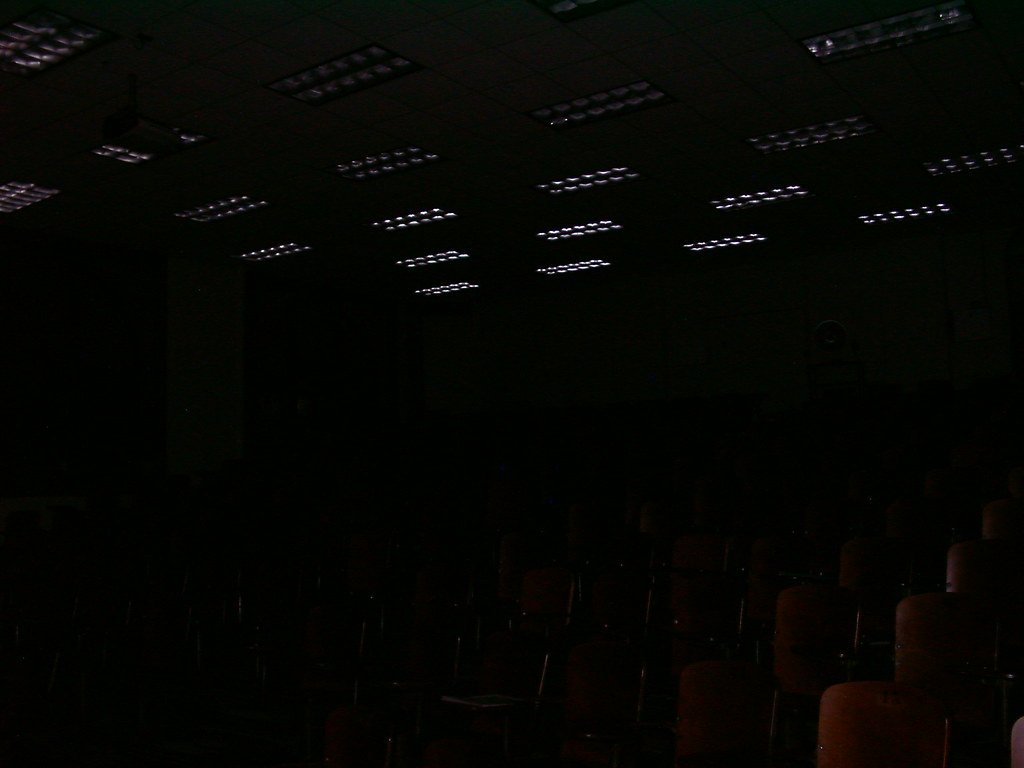 Auditorio de clases vacío, de noche, con las luces del techo encendidas